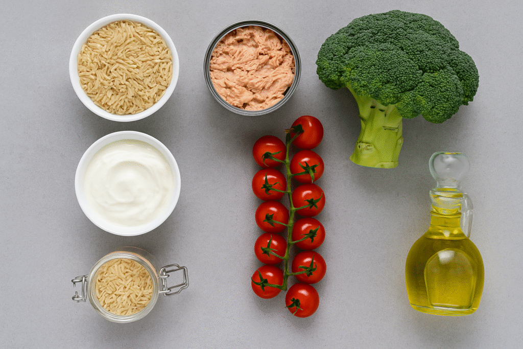 Mediterranean diet staples—brown rice, yogurt, tuna, broccoli, cherry tomatoes, and olive oil—arranged on a gray background.